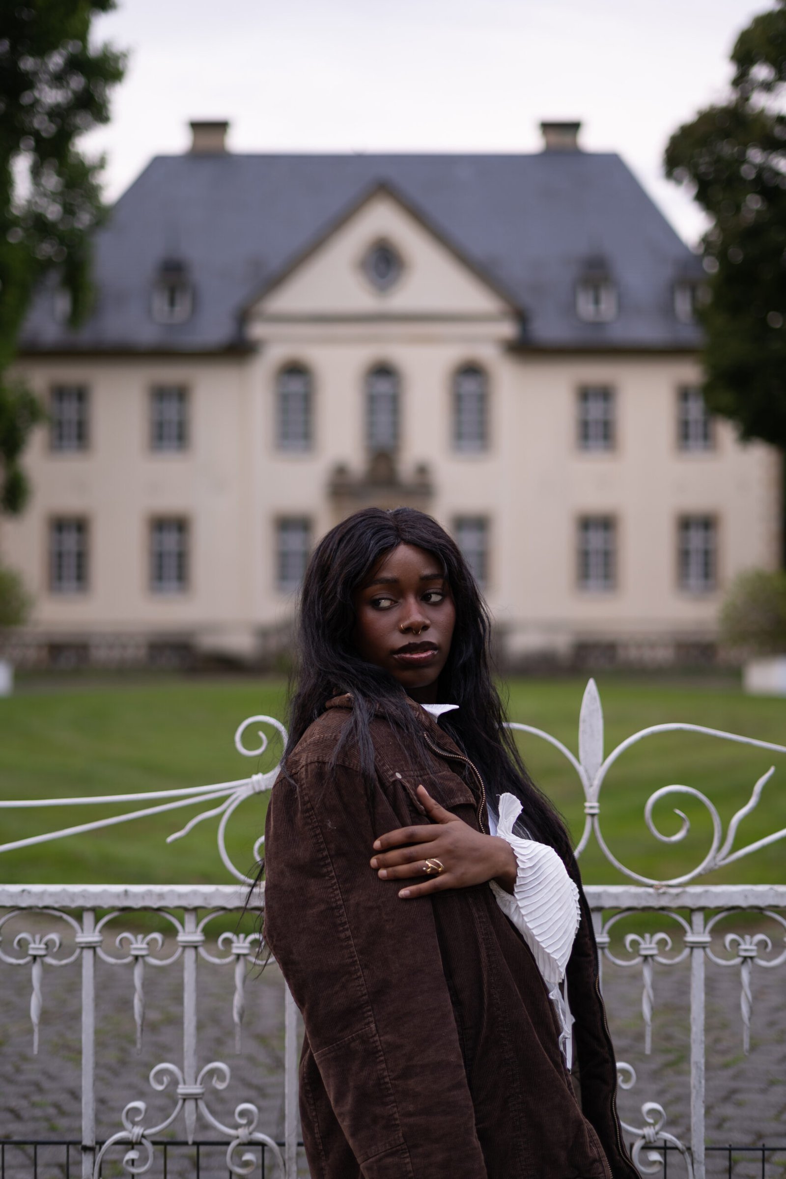 Professionelles Porträt-Shooting an einer Schloss-Location: Modell im weißen Kleid mit Blumen vor prachtvoller Architektur. Modernes Licht- und Bildkonzept für individuelle Fotoshootings. Foto: Mirovisuals.