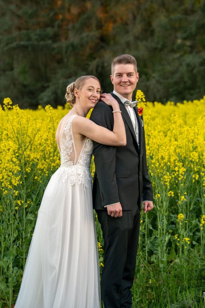 Romantisches Brautpaar-Shooting in der Natur: Hochzeitspaar vor einem blühenden Rapsfeld bei der Wasserburg Schelenburg. Authentische Hochzeitsfotos im Osnabrücker Land vom Hochzeitsfotograf Osnabrück.