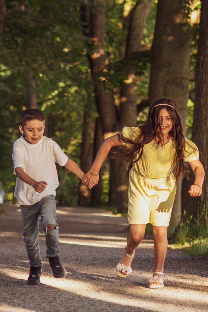 Lebendige Kinderfotografie im Freien, Geschwister laufen lachend durch den Park, Familienfotograf Mirovisuals Osnabrück.