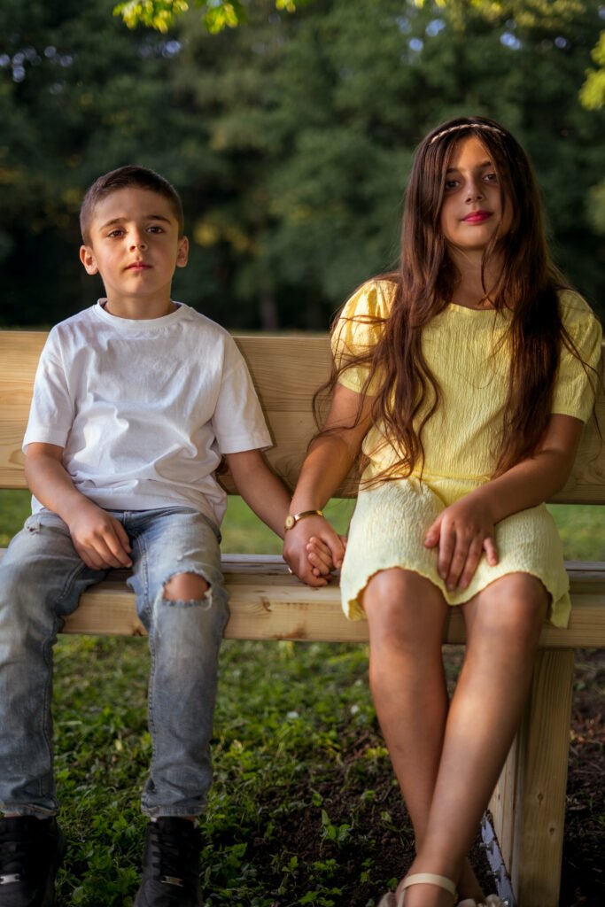 Authentisches Geschwister-Porträt auf einer Parkbank am Rubbenbruchsee, natürliche Familienfotos in Osnabrück von Mirovisuals.